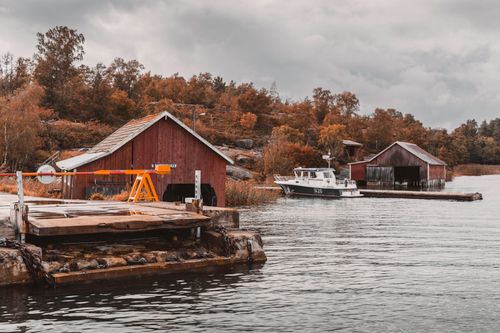 Free Picturesque autumn harbor scene with boat sheds and a ferry station in the Åland Islands. Stock Photo