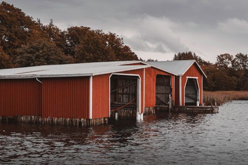 Free Scenic view of rustic red boat sheds by the water amidst autumn foliage on Åland Islands. Stock Photo