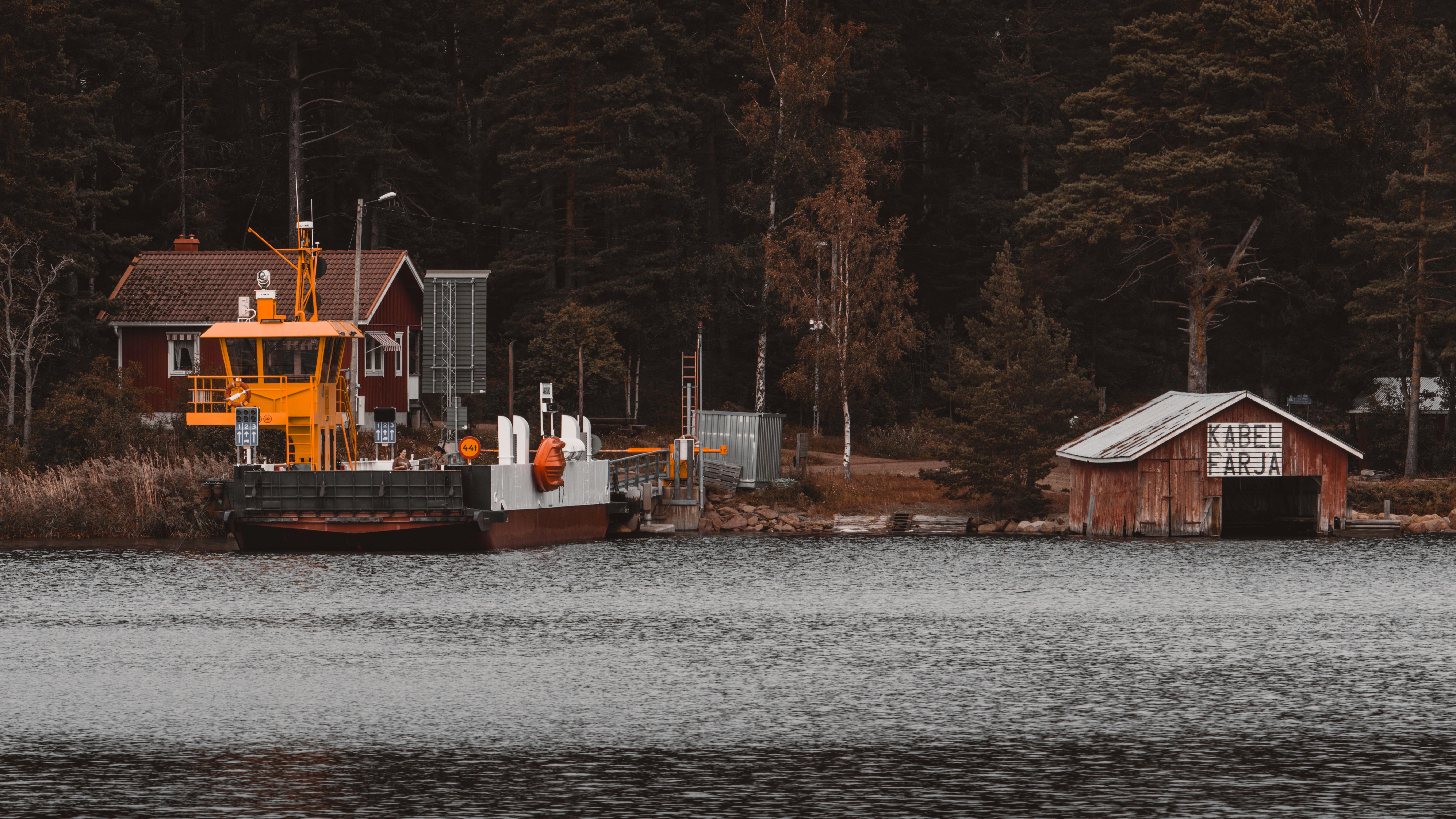 A serene boat shed by a ferry station in the Åland Islands, Finland, surrounded by dense forest.