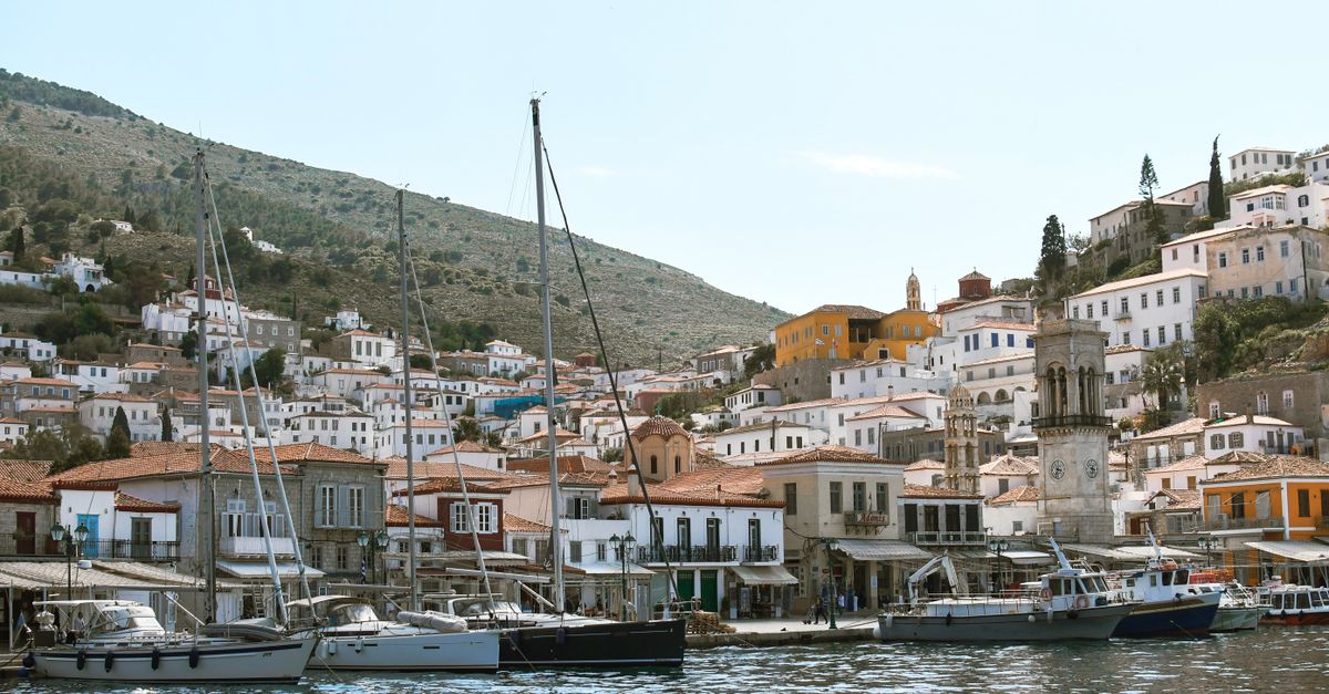 Charming Hydra town with boats moored along the scenic waterfront, captured on a sunny day.