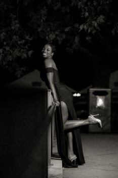 Striking black and white photo of a woman posing elegantly outdoors at night.