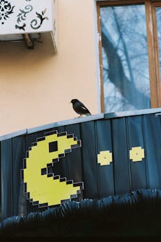 A retro-themed Pac-Man sign with a bird perched in Almaty, Kazakhstan.