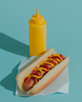 Delicious hot dog topped with ketchup and mustard on a napkin, bright background.