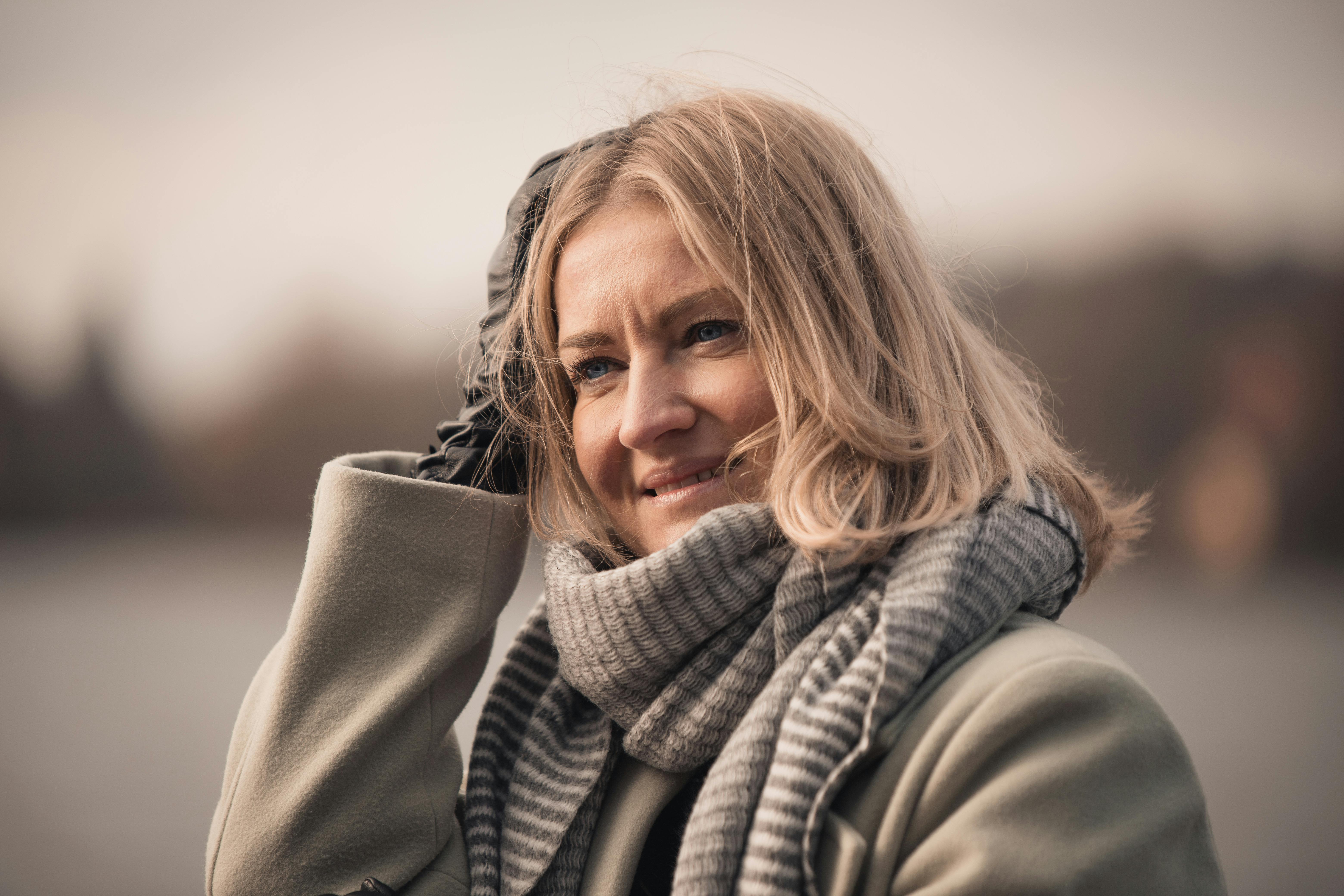 Free Smiling woman in cozy autumn attire near a lake in Weßling, Germany. Stock Photo
