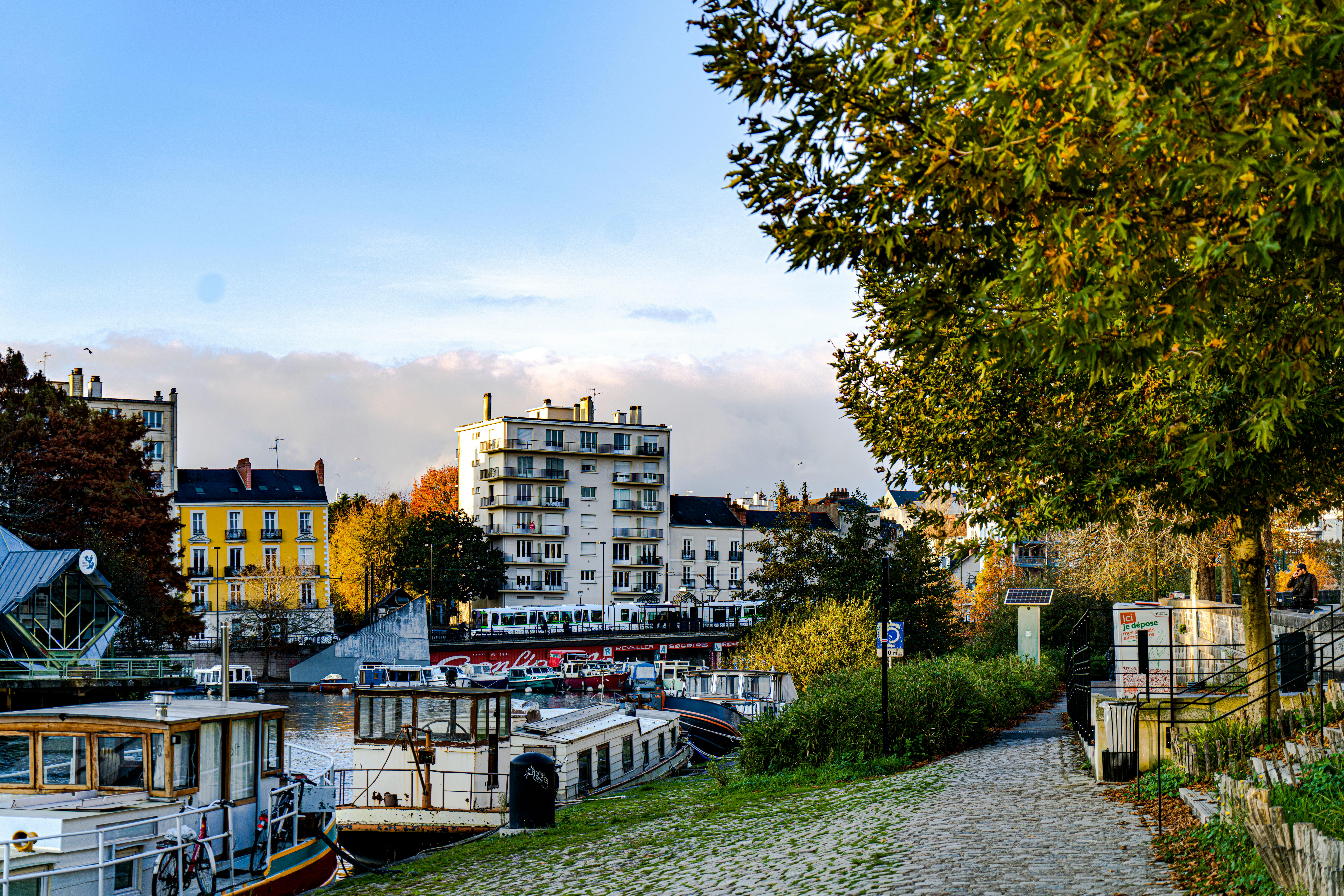 Charming riverside view of Nantes, France, showcasing boats, buildings, and autumn scenery.