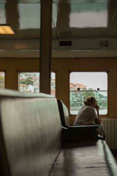 Woman on Istanbul ferry enjoying cityscape through the window.