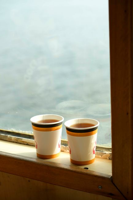 Two steaming cups of tea on a window ledge with a view of Istanbul waters.
