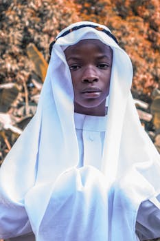 Portrait of a young man wearing a traditional white robe with an autumn background.