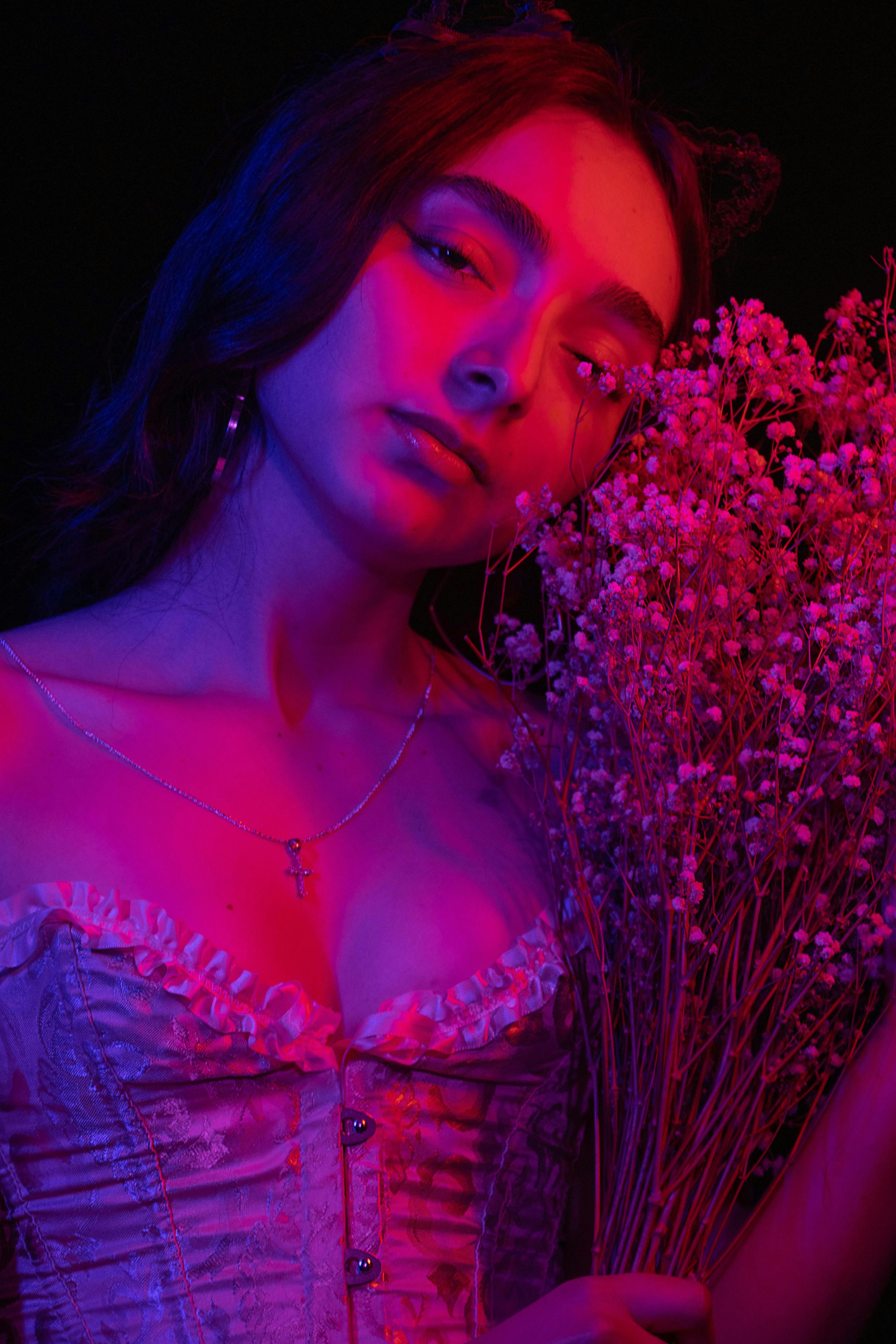 Gratis Potret artistik seorang wanita dalam pencahayaan neon yang terang, menonjolkan keanggunan dan keindahan bunga. Foto Stok