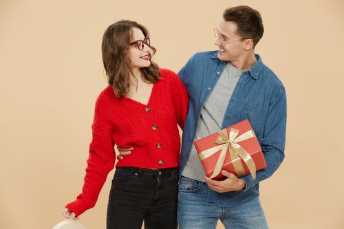 Free A cheerful couple wearing glasses celebrate together with a gift box in a festive setting. Stock Photo