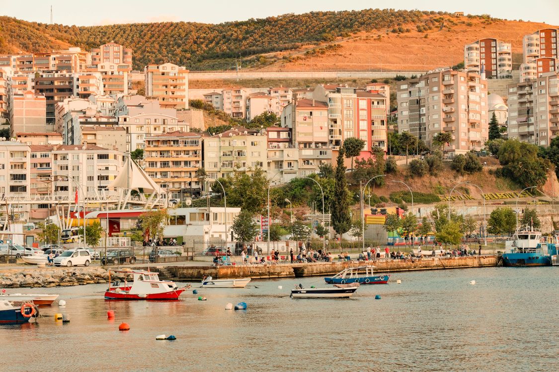 Free Scenic view of a coastal city with boats, hillside, and residential buildings. Stock Photo