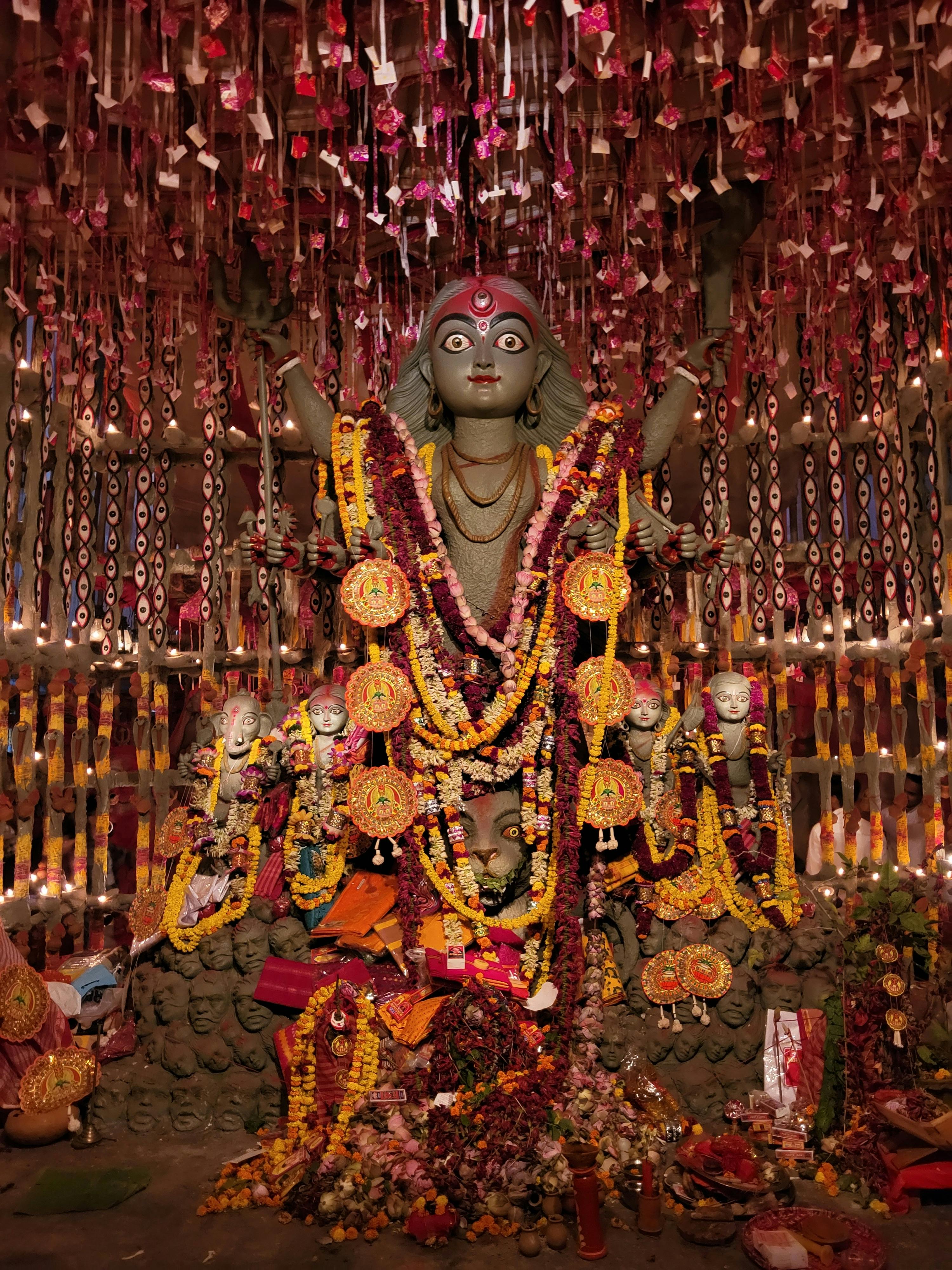 Colorful Durga idol adorned with flowers in a Kolkata pandal during Durga Puja festival.