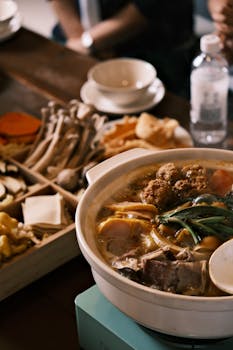 A steaming Asian hot pot with various ingredients, perfect for a cozy meal.