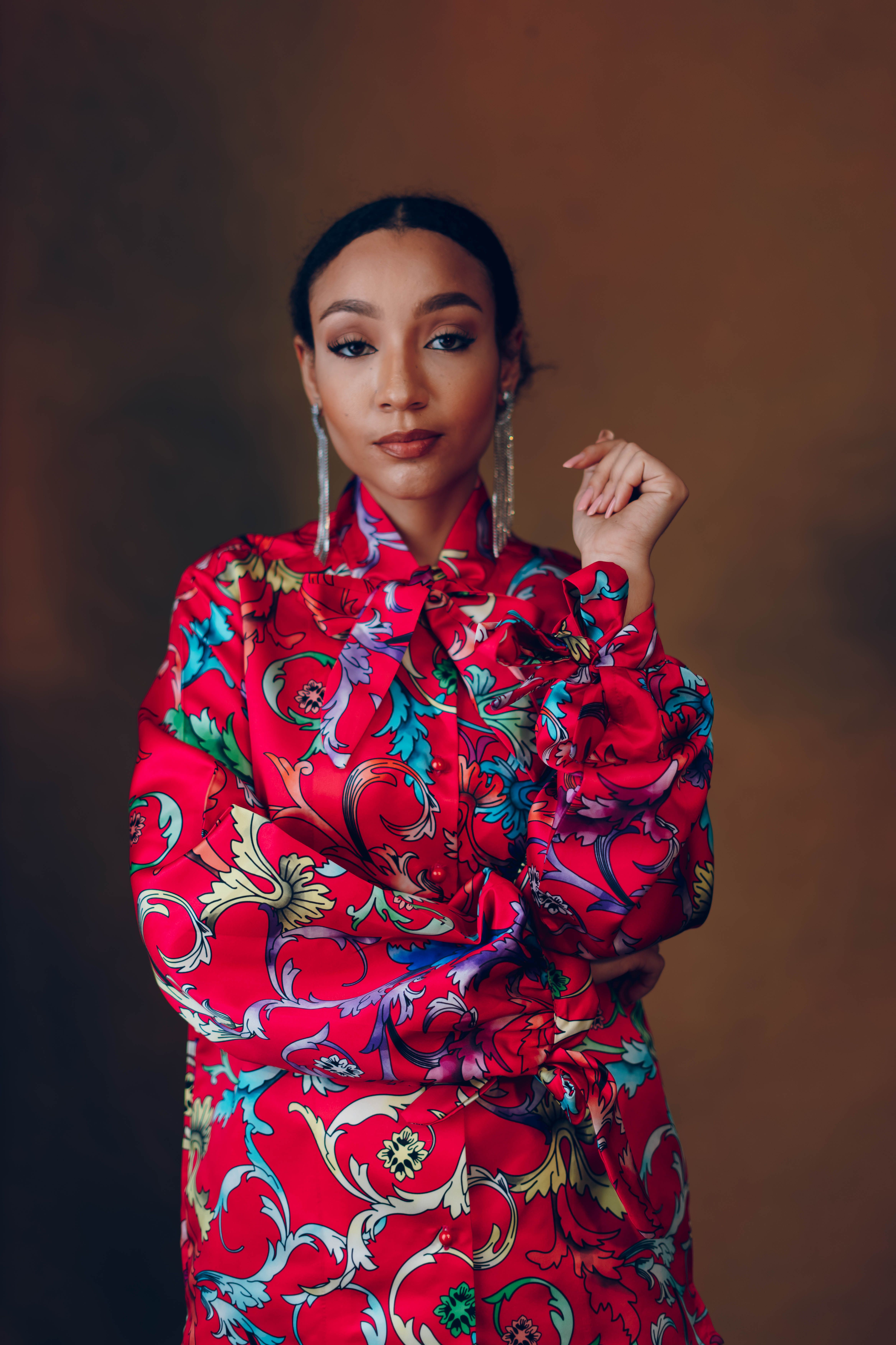 A striking portrait of an elegant woman in a colorful, patterned dress, exuding confidence and style.