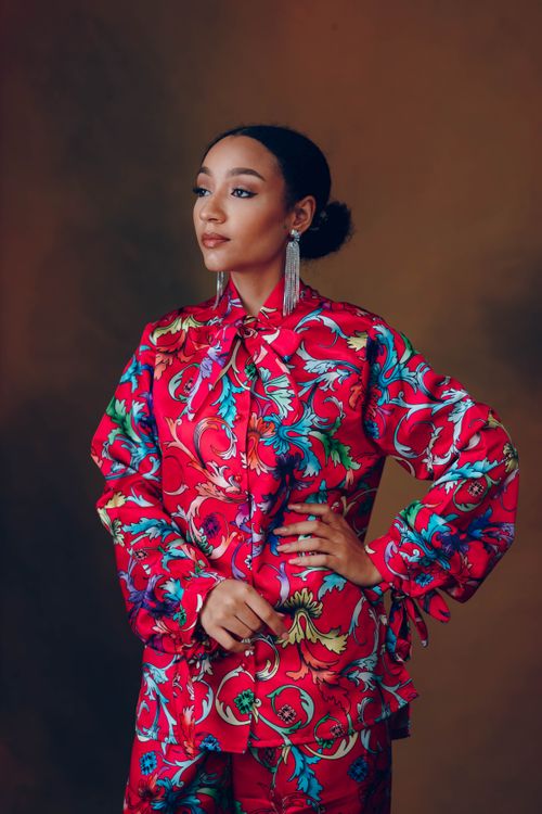 Free Elegant portrait of a woman in a vibrant floral dress exuding confidence and style. Stock Photo
