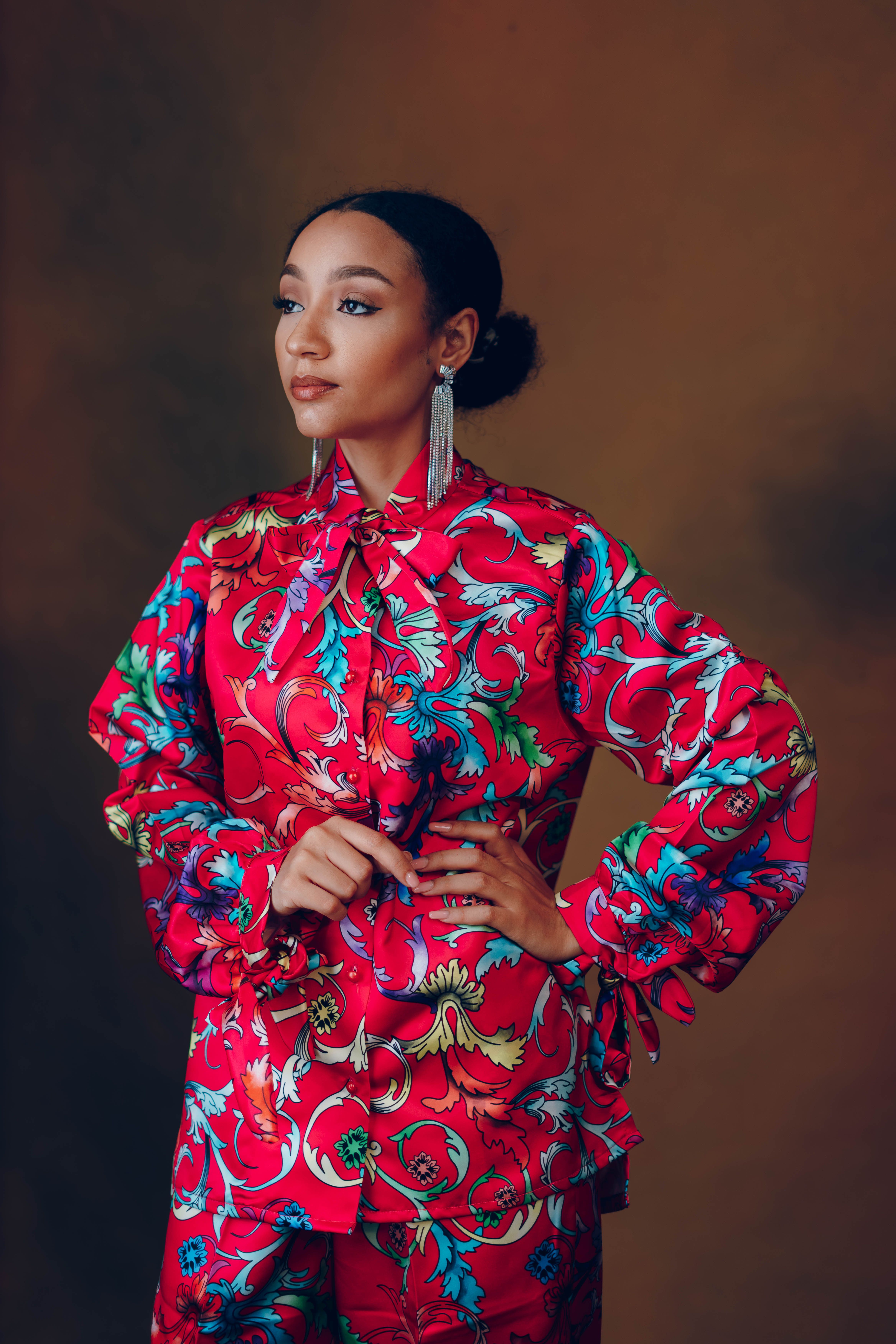 Fashion portrait of a woman in a vibrant floral dress against a warm background.