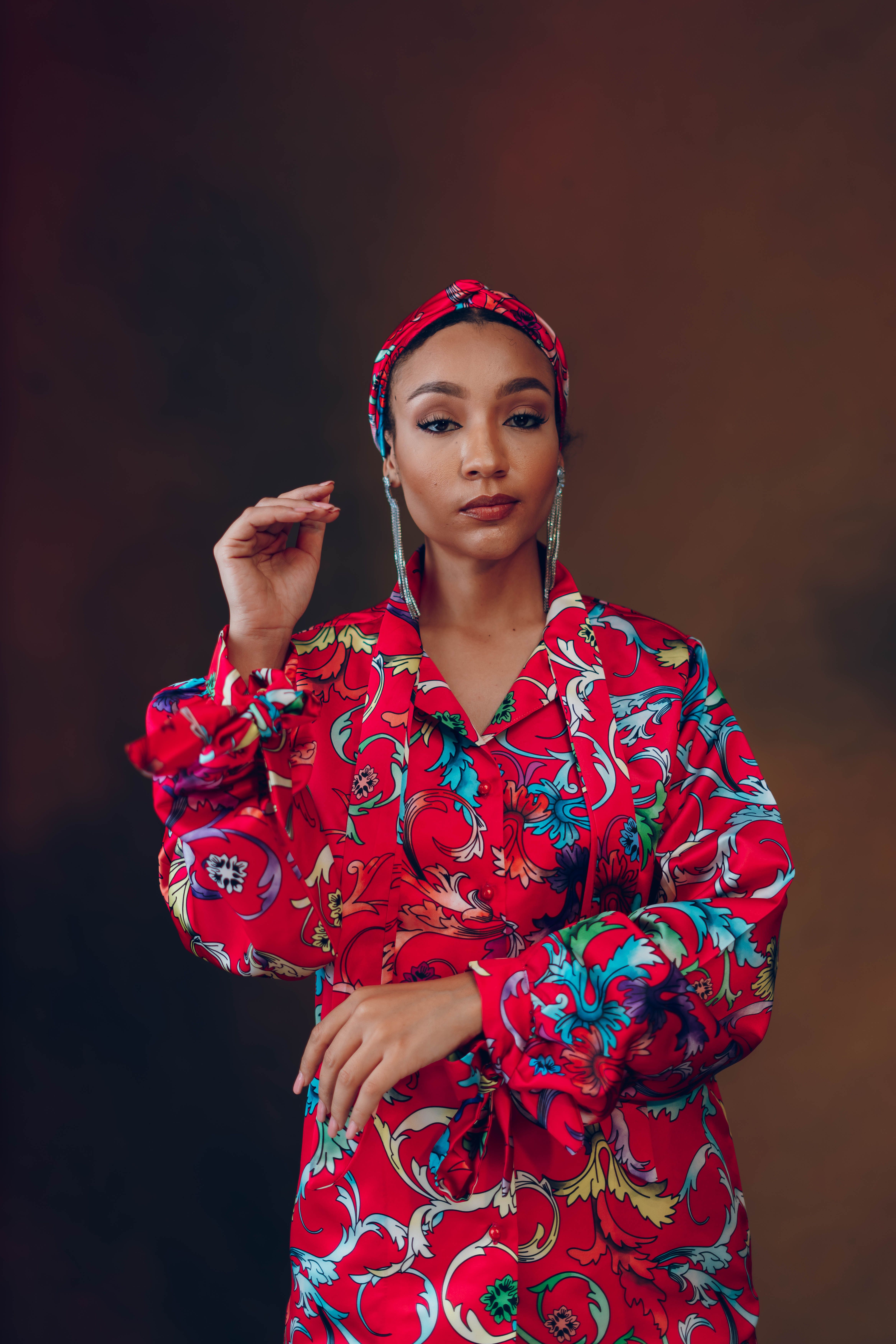 Elegant portrait of a woman in vibrant red attire with floral patterns.