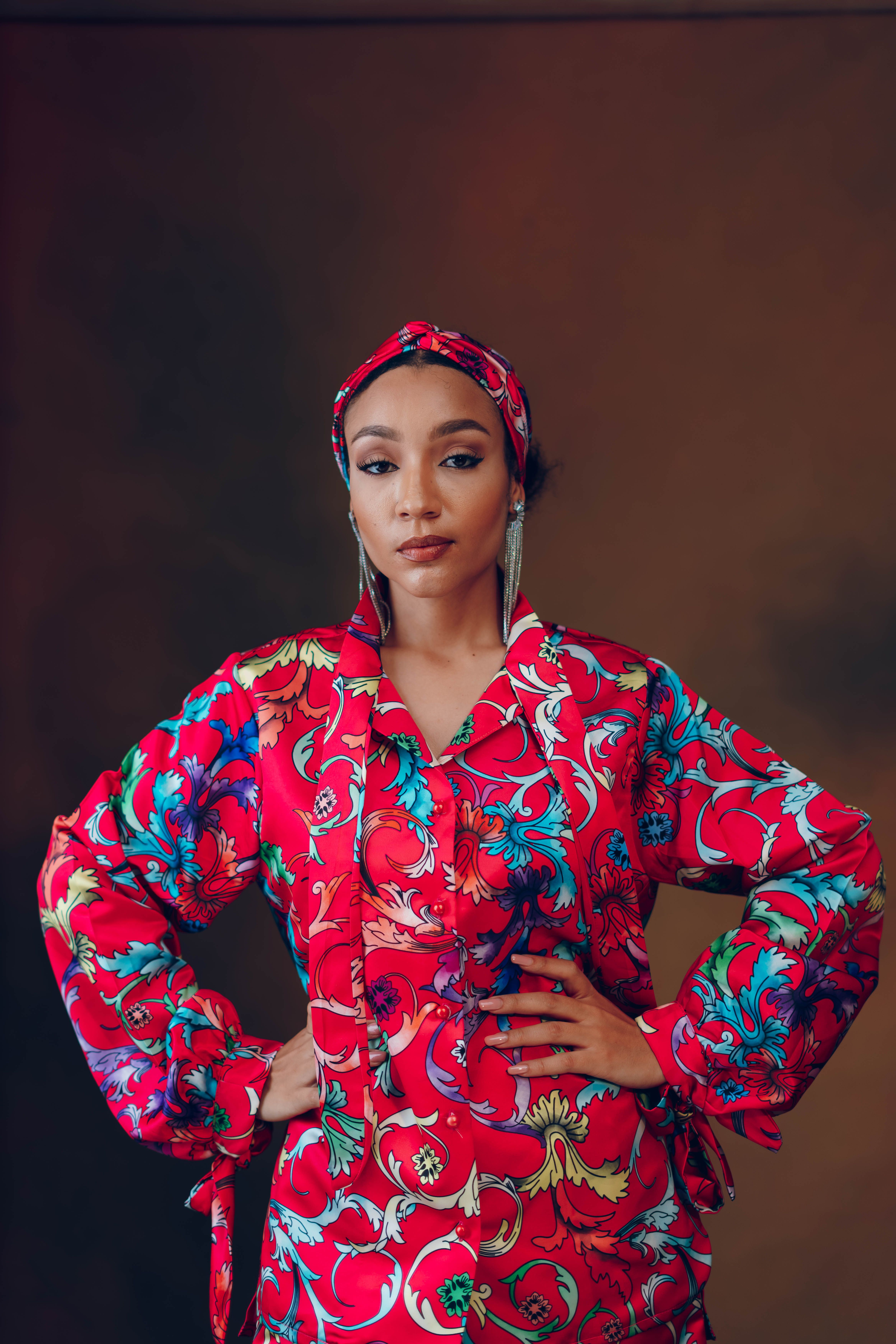 Elegant model in vibrant floral attire striking a confident pose indoors.