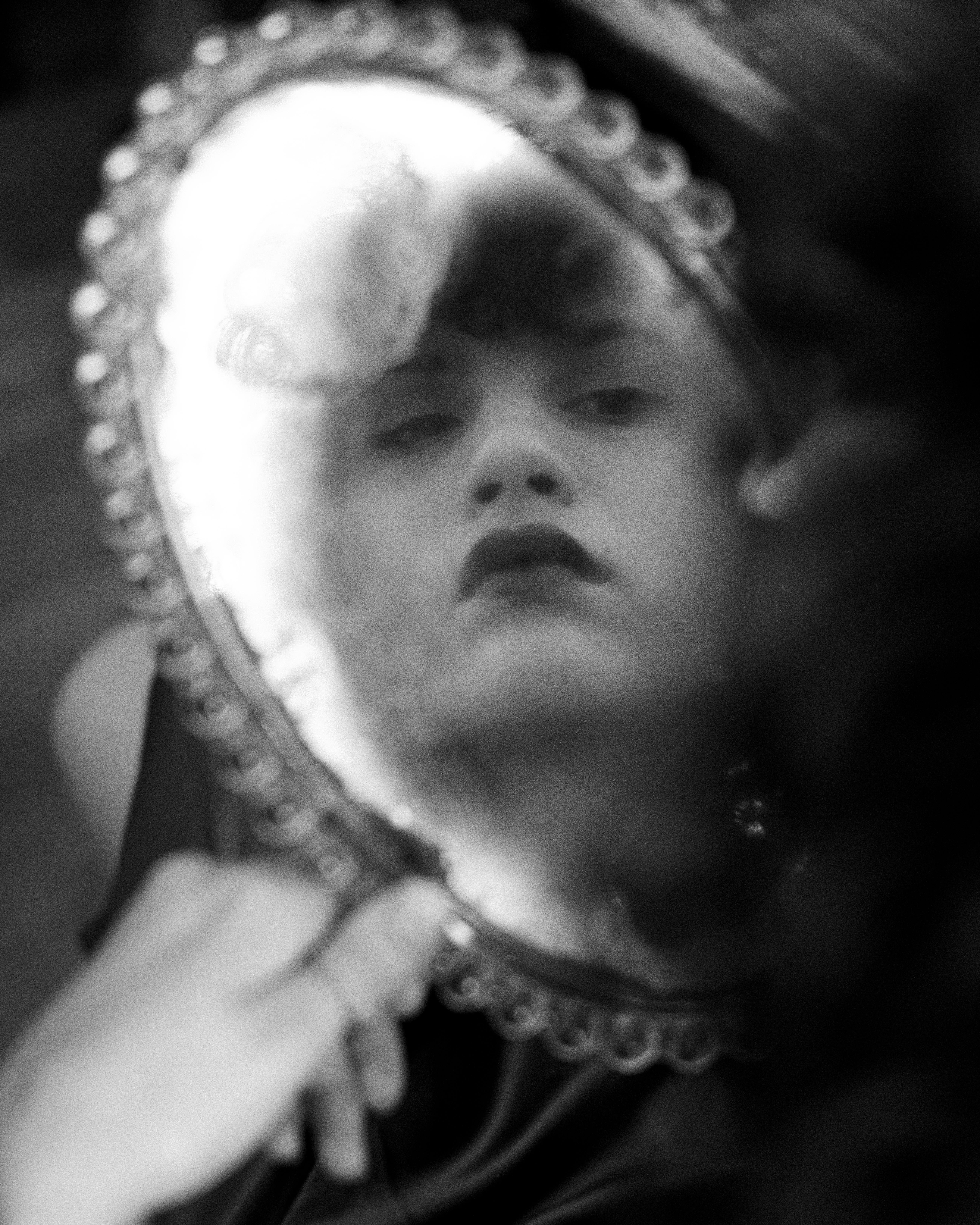 Artistic black and white portrait reflected in an ornate vintage mirror.