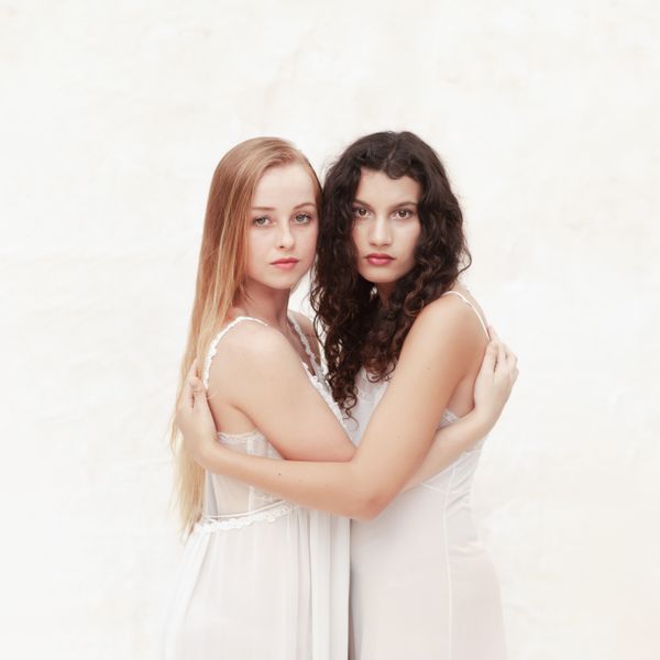 Two women in white embracing against a light backdrop — photo by Katy Walters on Pexels
