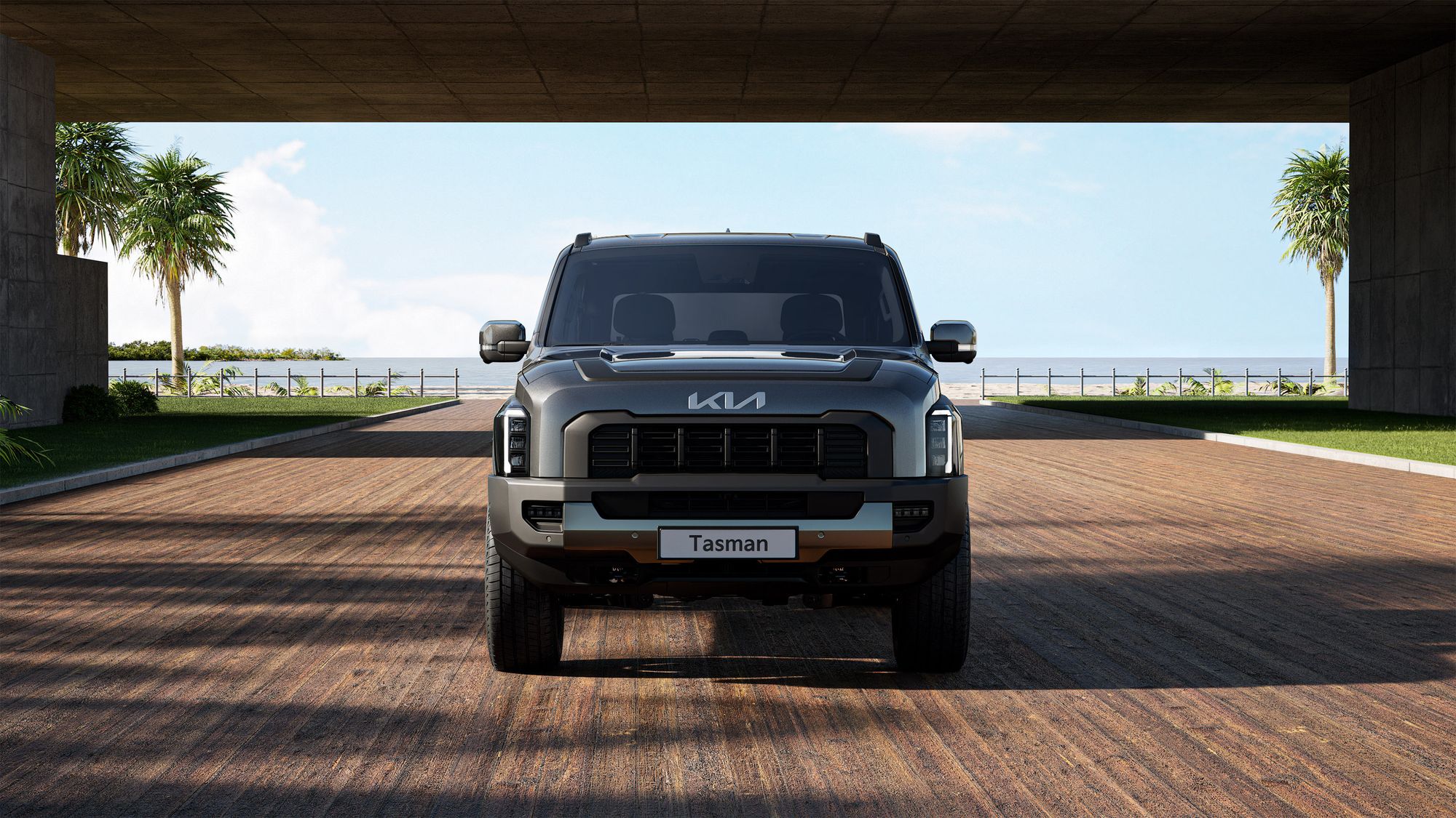 Sleek Kia Tasman pickup truck on a sunny coastal road with ocean views.
