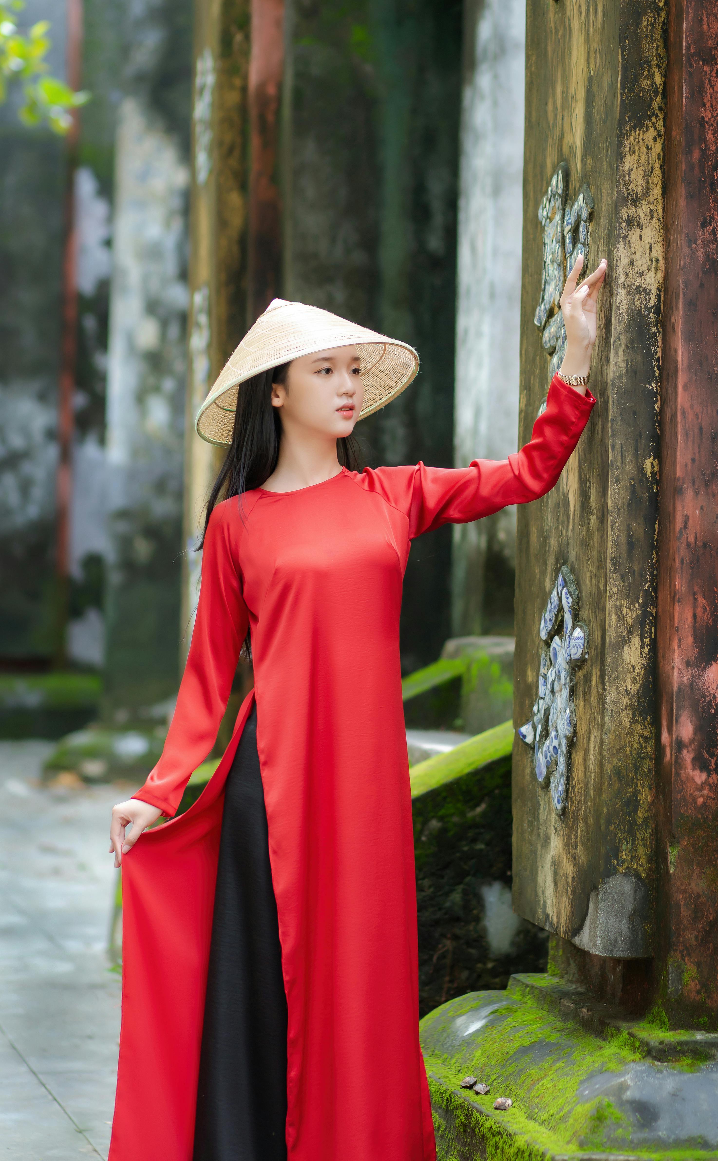 Traditional Vietnamese woman in red Ao Dai at ancient temple in Hoi An.