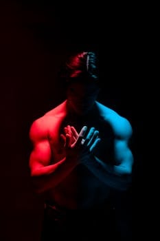 Moody studio portrait of a male bodybuilder with red and blue lighting.