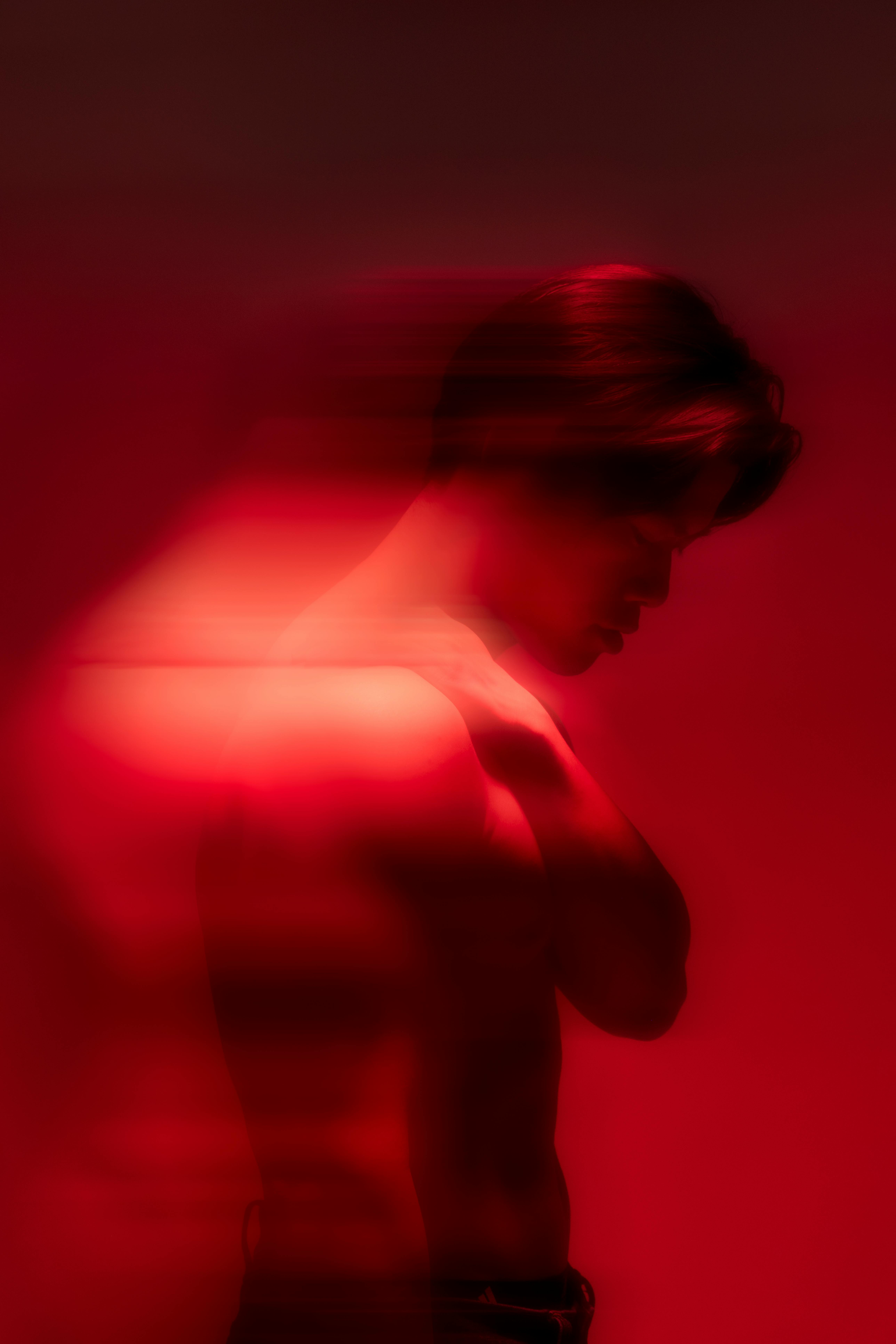 Moody artistic silhouette of a man in dramatic red lighting.