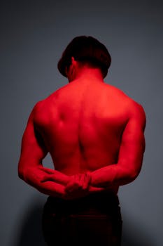 Artistic studio silhouette of a muscular man in red lighting, creating a moody atmosphere.