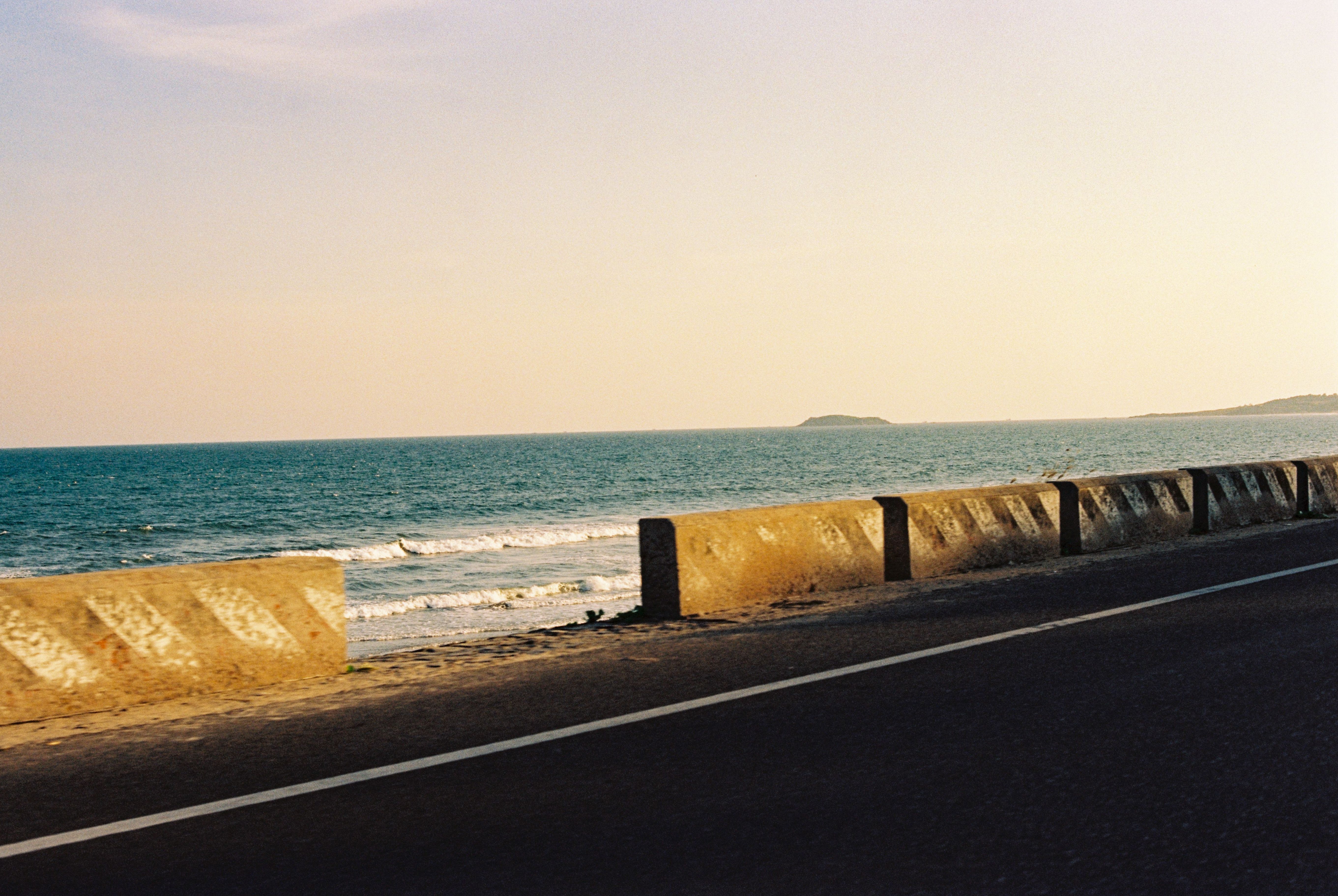 A serene coastal road and ocean view in Phan Thiết, Việt Nam during sunset.