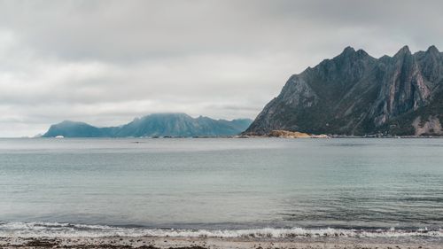 Free Tranquil scenery of Lofoten Islands' mountains with a calm sea under a cloudy sky. Stock Photo