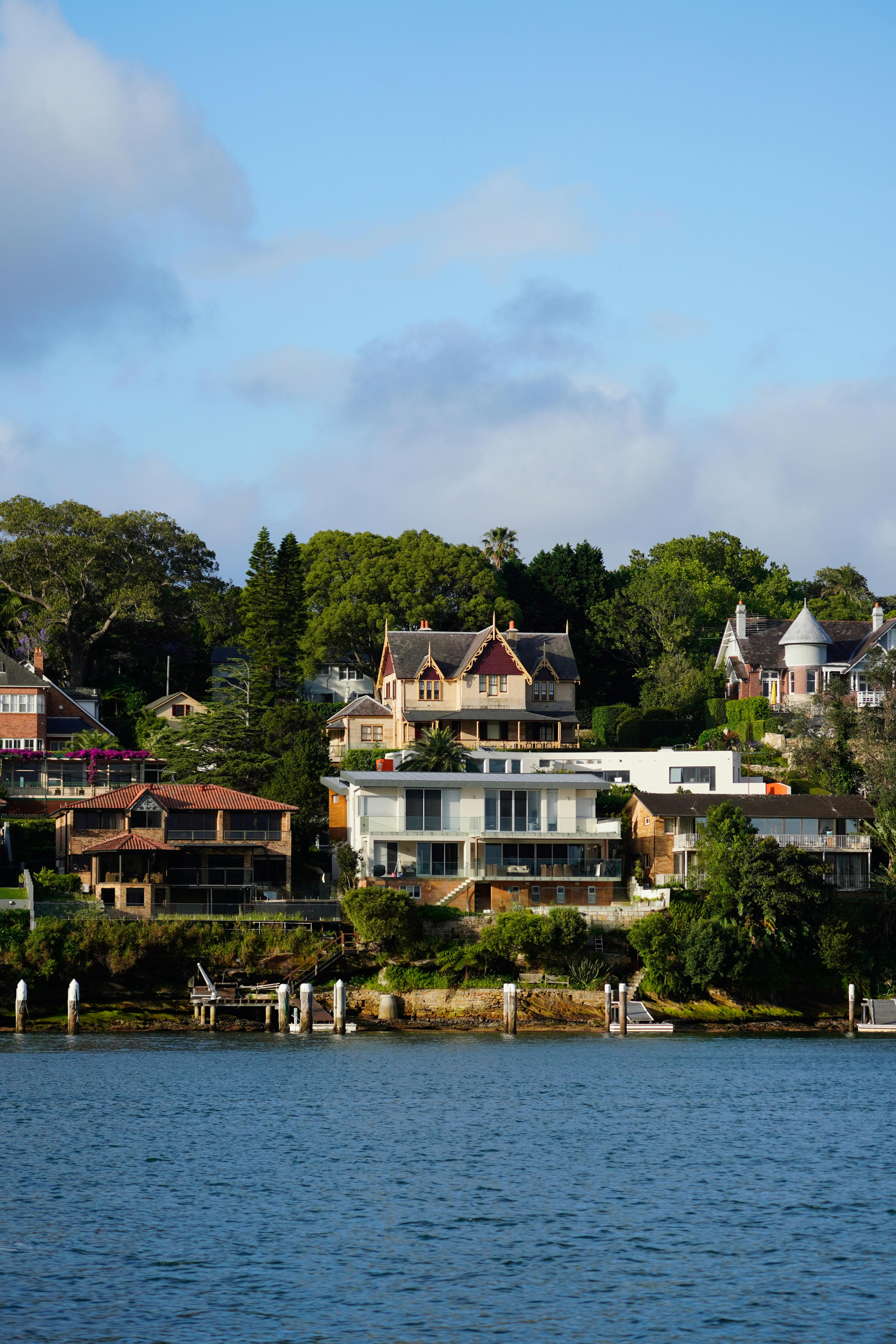Scenic view of beautiful houses along a serene river, showcasing lush greenery.
