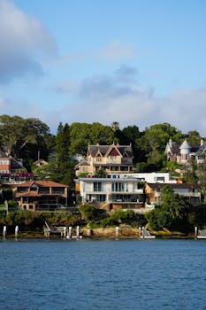 Scenic view of beautiful houses along a serene river, showcasing lush greenery.
