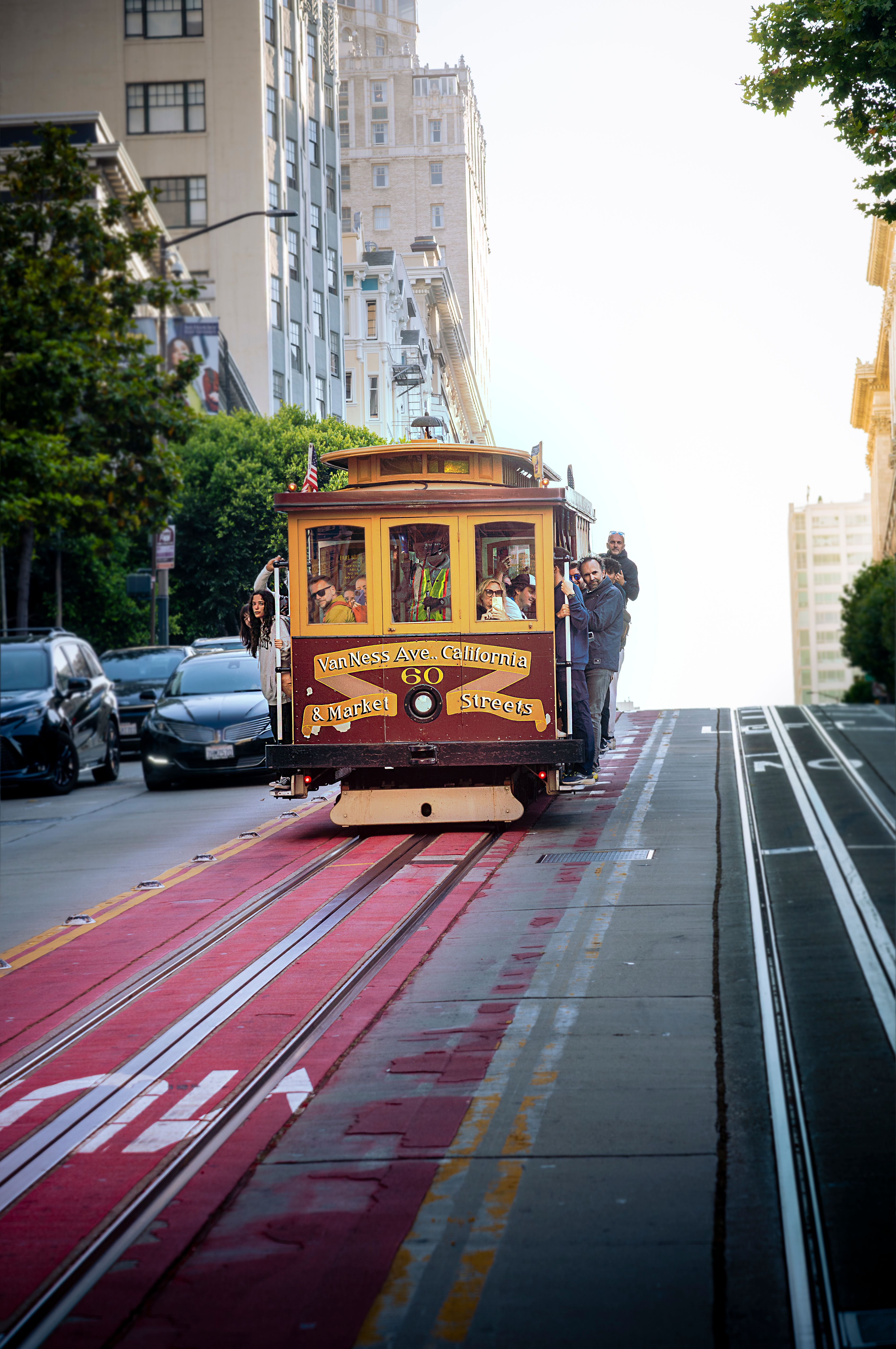 gratis De klassieke kabelbaan van San Francisco rijdt bergopwaarts door een zonnige straat en legt de stedelijke charme vast. Stockfoto