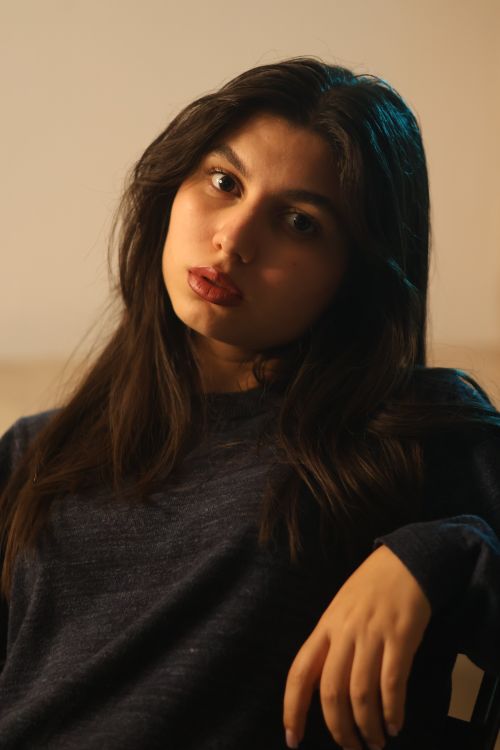 Free Close-up portrait of a woman with long dark hair wearing a dark sweater, looking at the camera serenely. Stock Photo