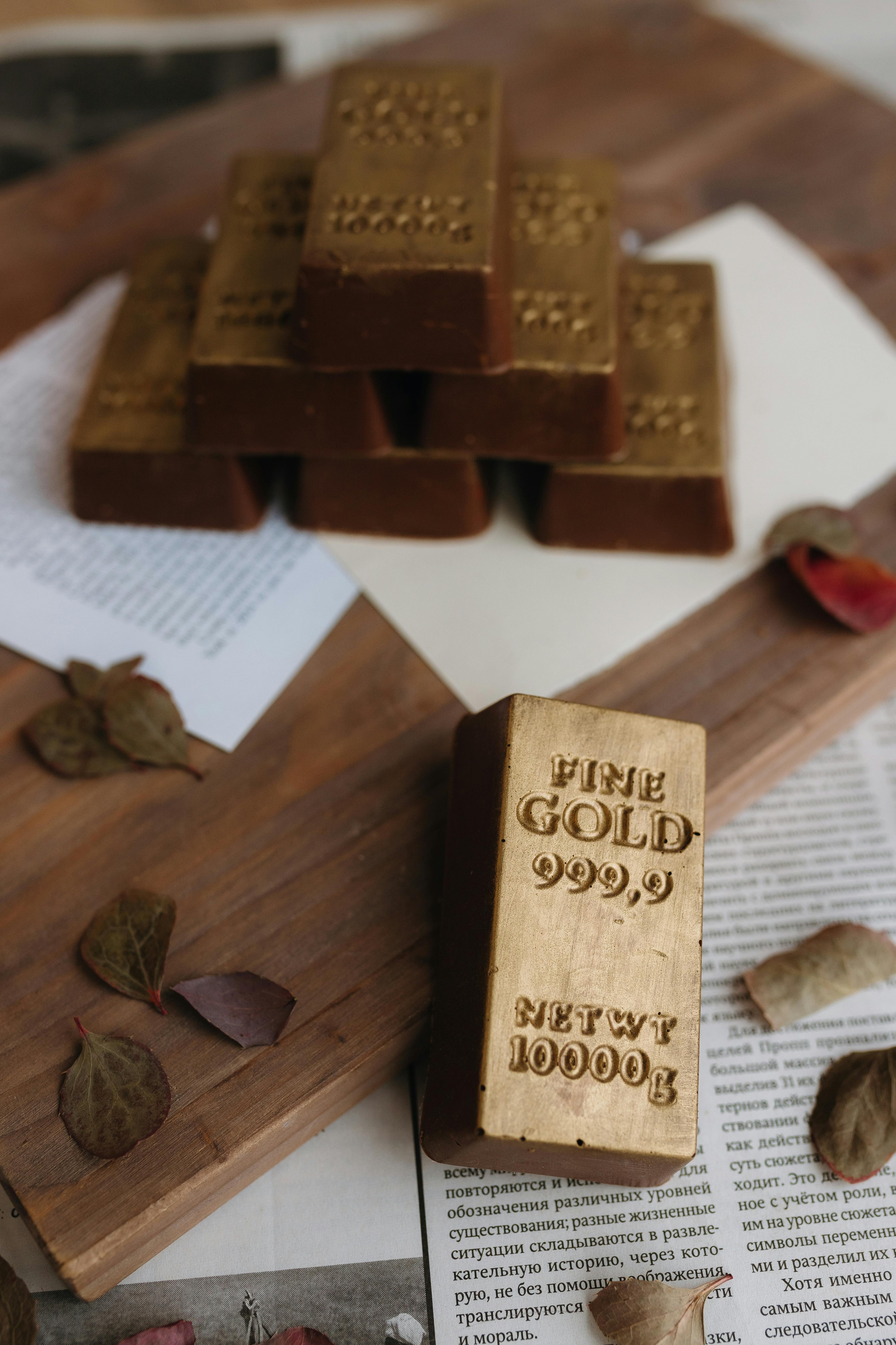 gold bars on rustic table with leaves and papers