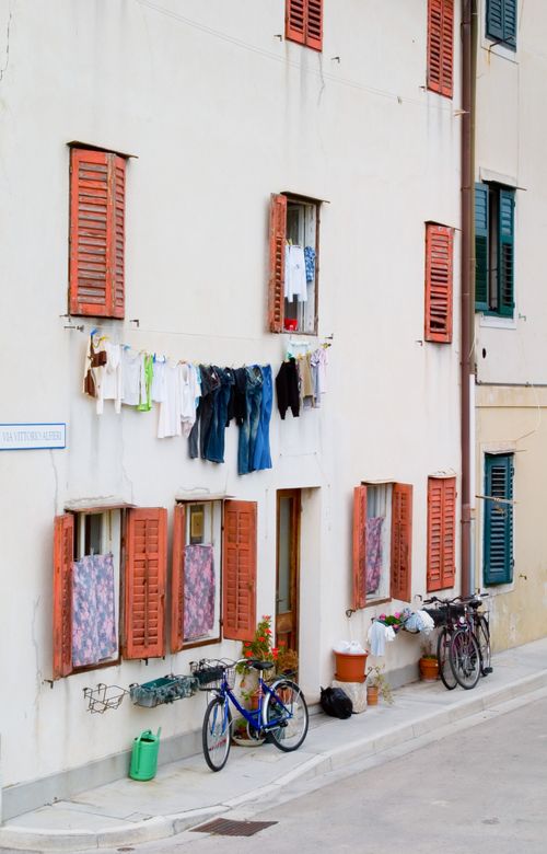 Free Colorful street scene in Italy with hanging laundry and bicycles outside a rustic building. Stock Photo
