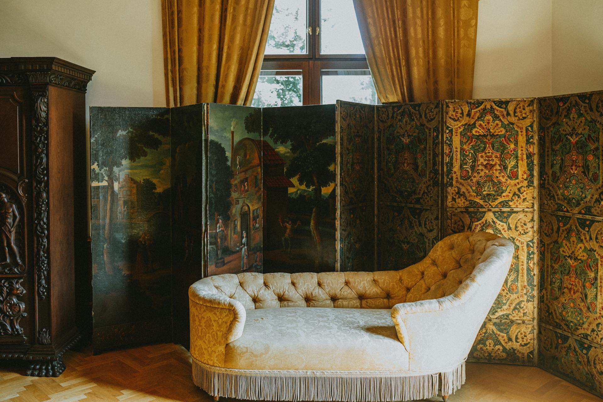 Luxurious vintage interior featuring an antique chaise longue and ornate room divider with rich golden hues.