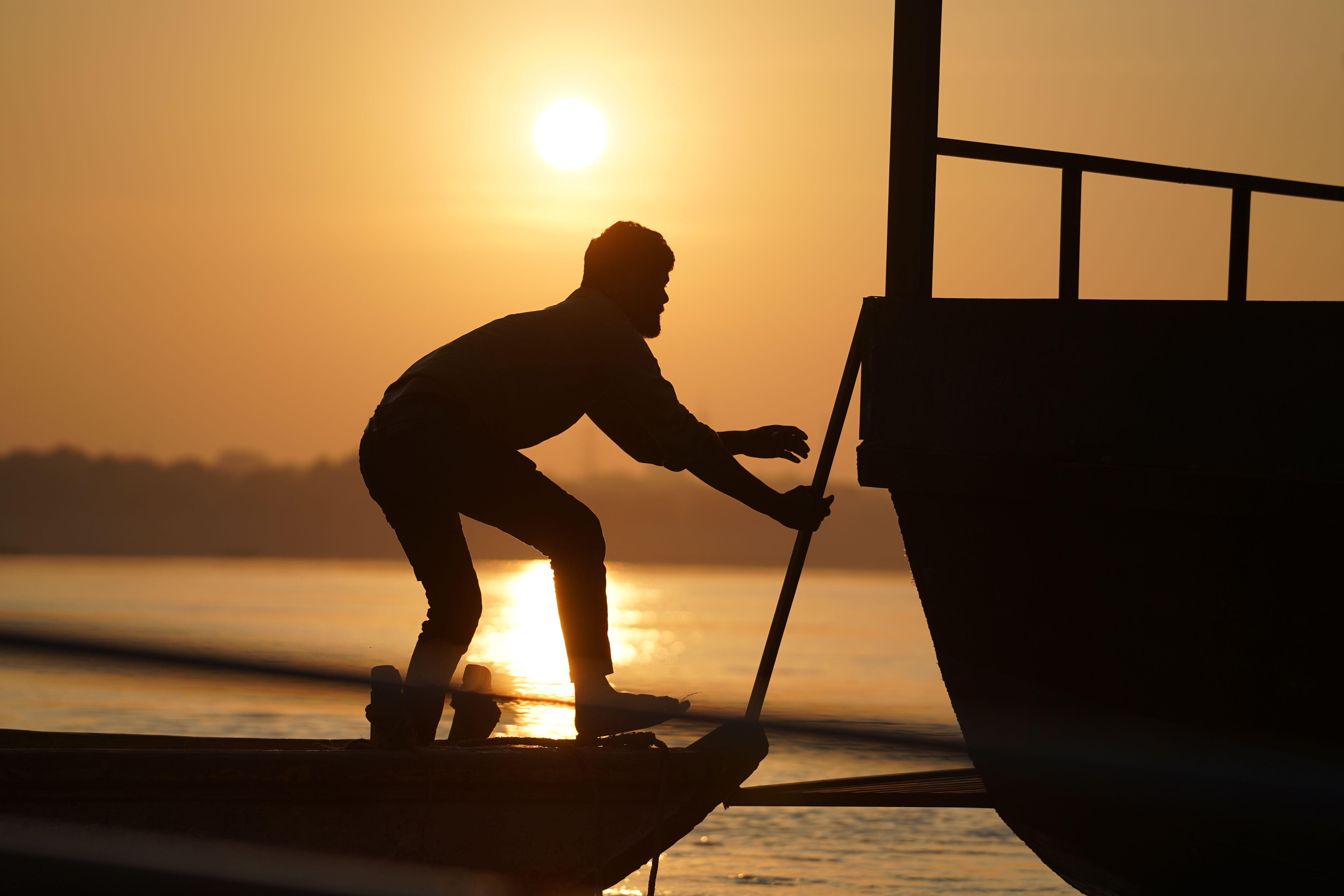 Silhouette of Man on Boat During Golden Sunset · Free Stock Photo