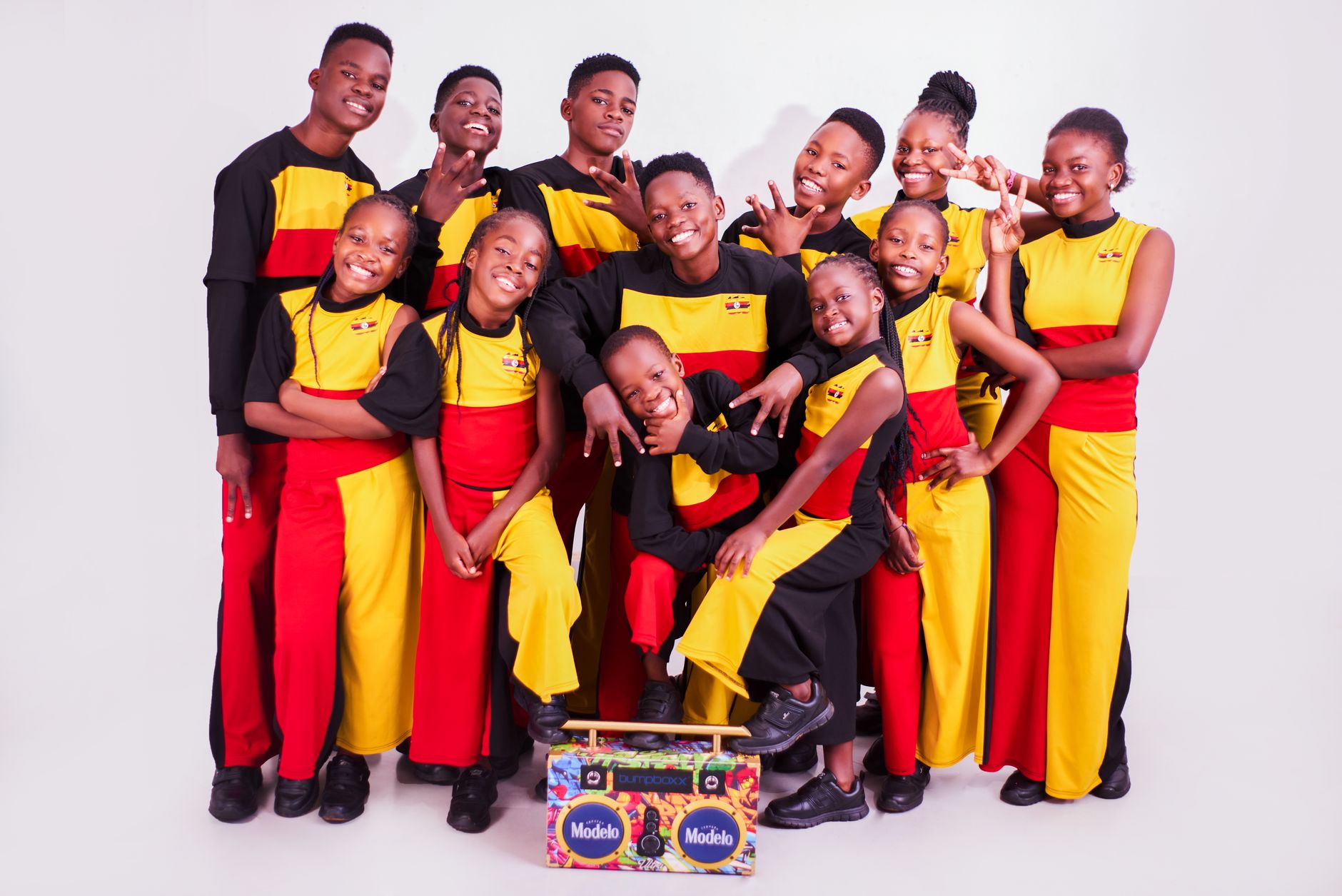 A joyful group of Ugandan youth posing in bright, colorful attire with cheerful expressions.