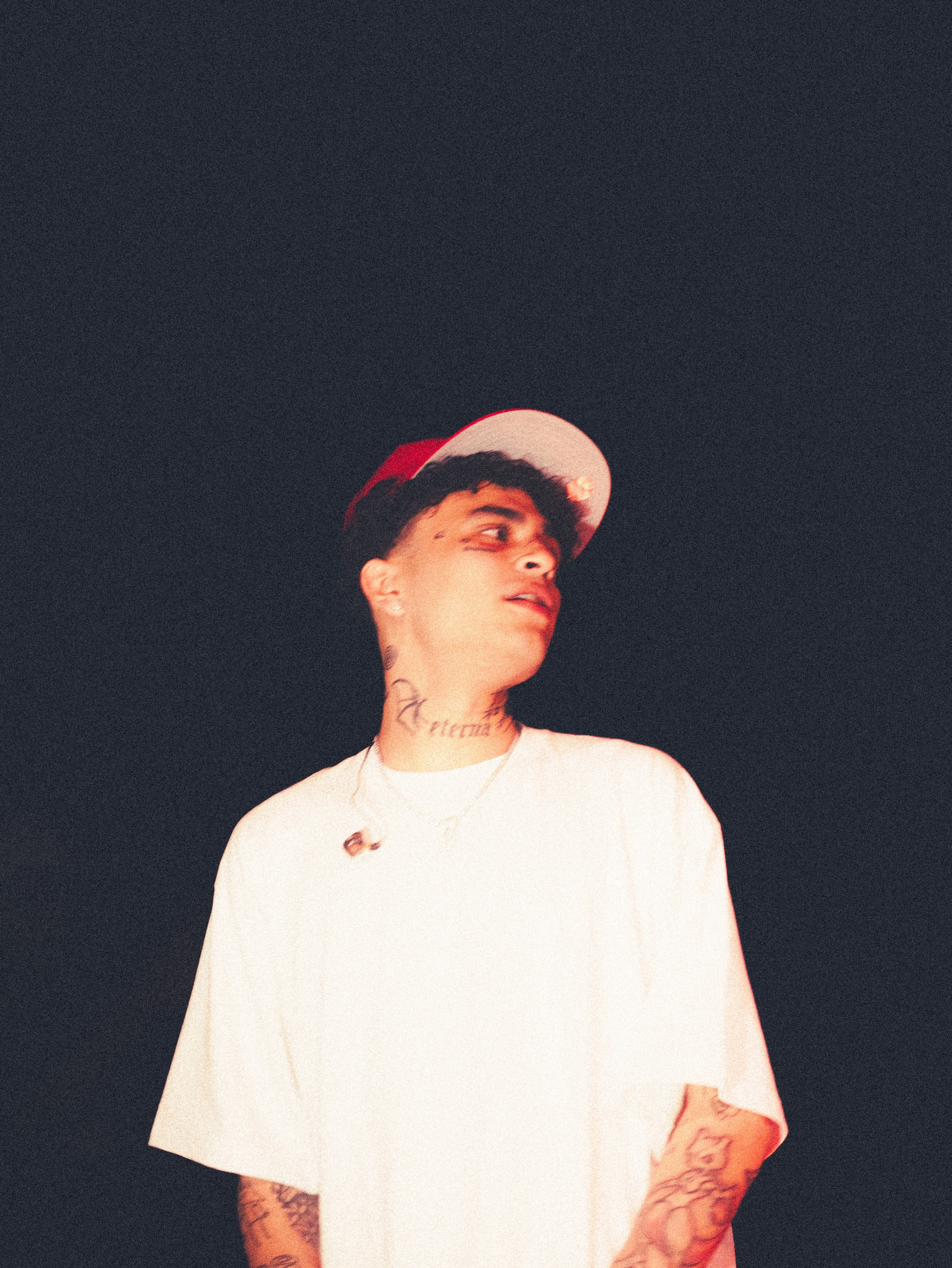 Stylish young man wearing a white shirt and cap, captured at night.