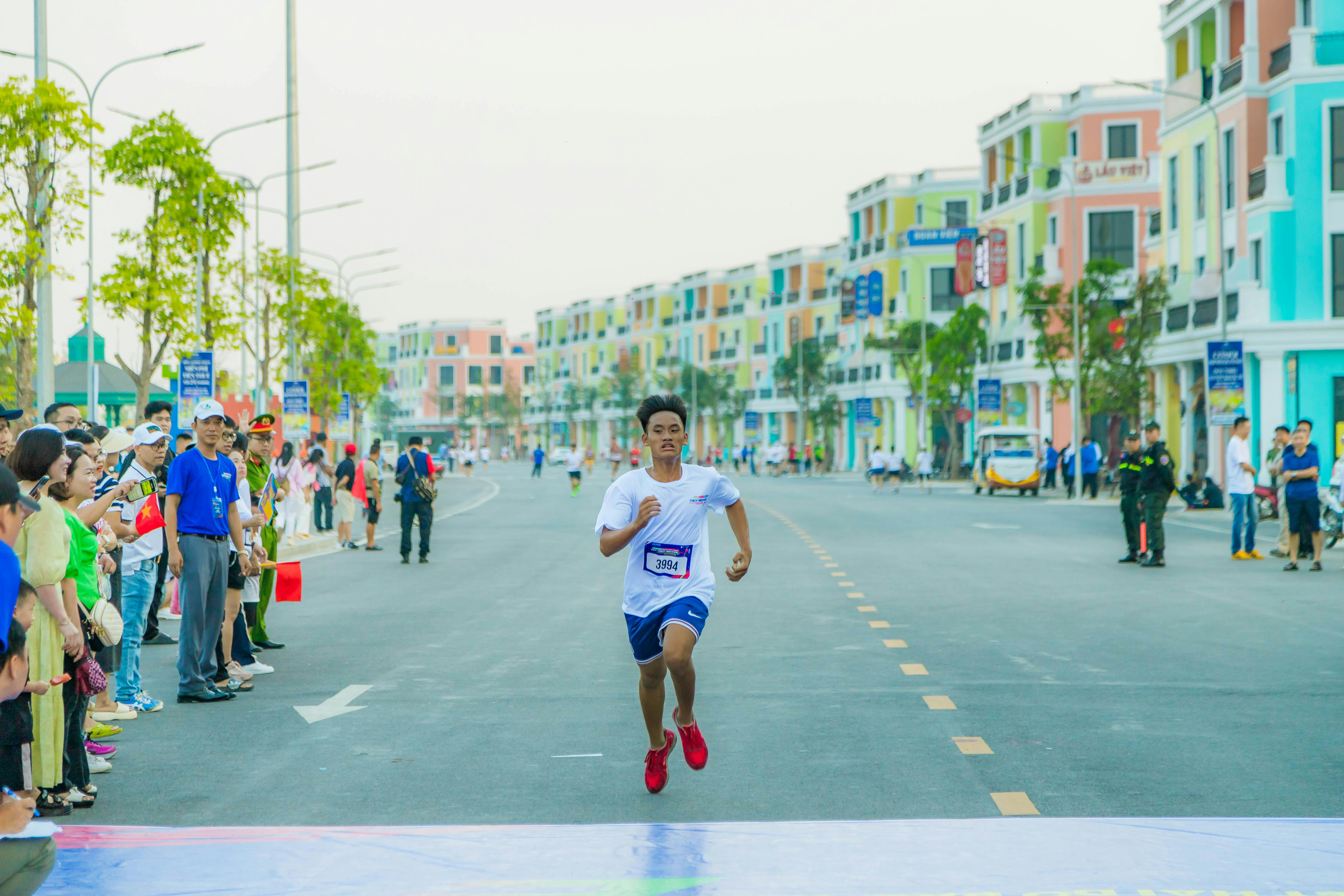 Runner reaching the finish line in a vibrant marathon in Hải Phòng's colorful streets.