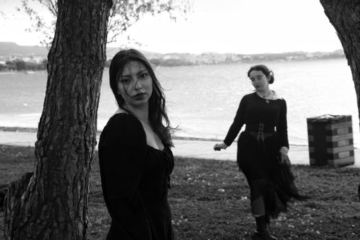 Artistic outdoor black and white portrait of two women by a lake, capturing a moody atmosphere.