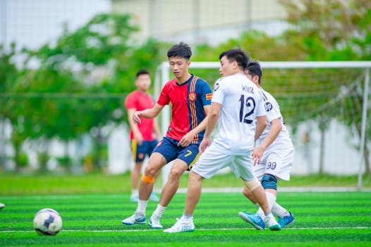 Young male athletes playing soccer on a lush green field in Hà Nội.