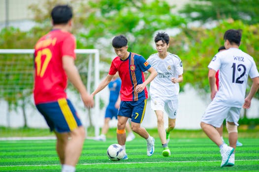 Young players engaged in a soccer match on a vibrant green field in Hanoi.