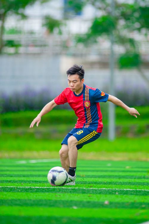 Free A young Asian male in a soccer jersey playing on a green field in Hanoi, Vietnam. Stock Photo