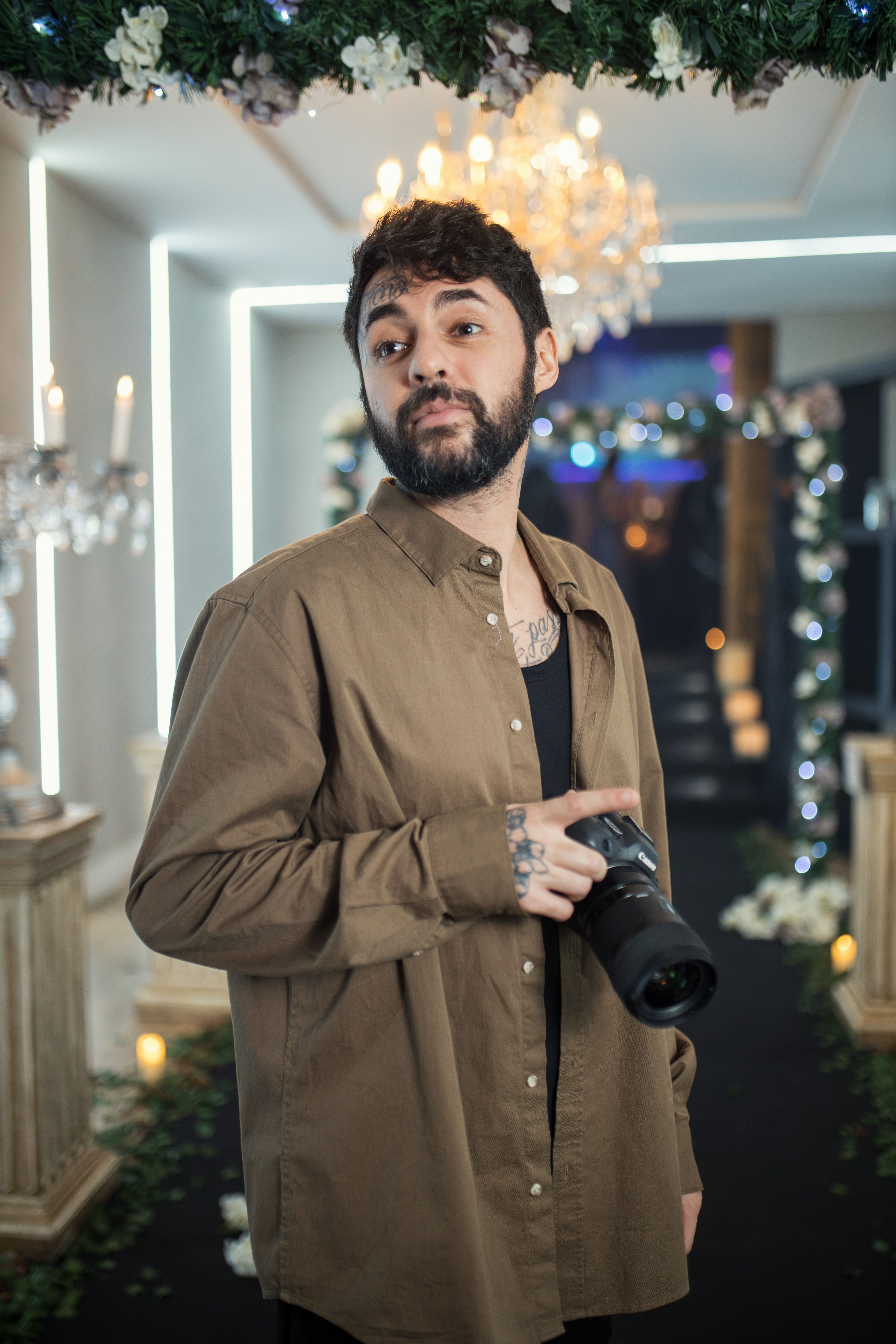 Photographer holding a camera in a beautifully decorated indoor venue.