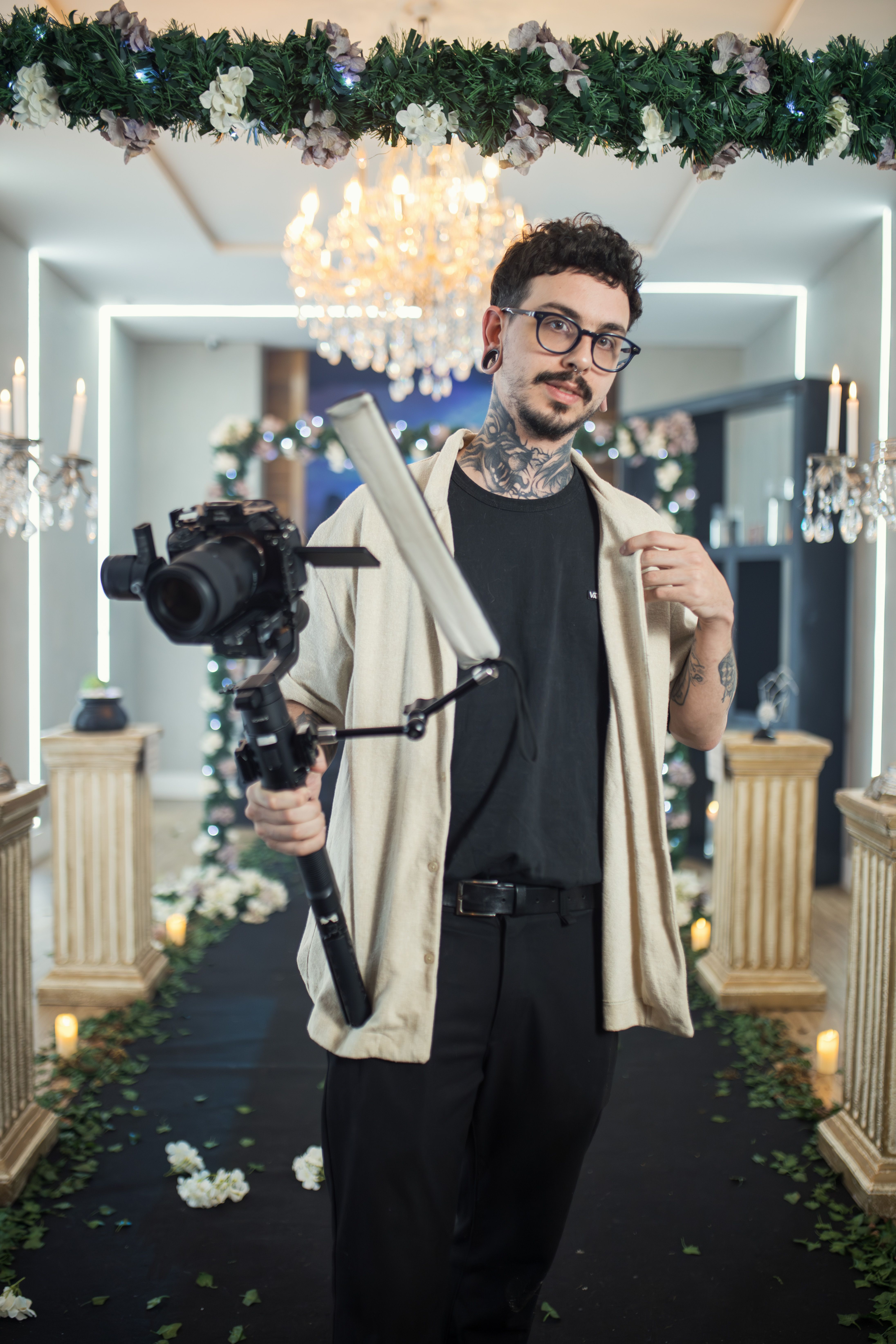 Photographer holding camera gear at upscale, indoor wedding event.