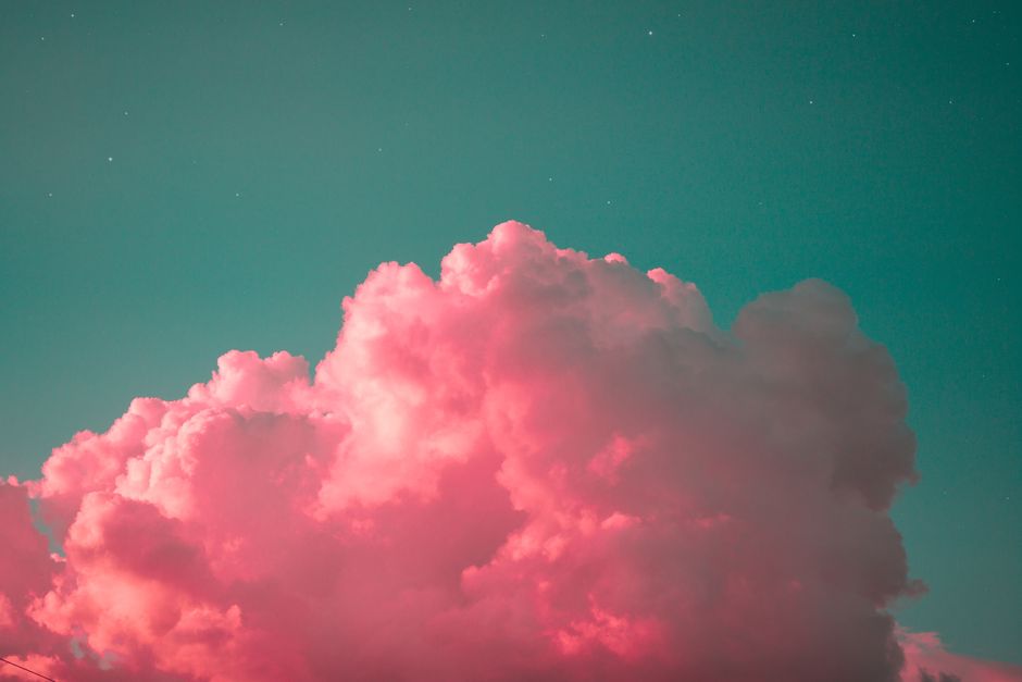 A stunning display of vibrant pink clouds set against a teal sky during twilight, creating a dreamy atmosphere.