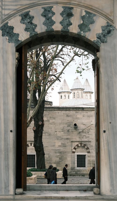 Free View through an ornate stone archway to historic architecture with people walking. Stock Photo